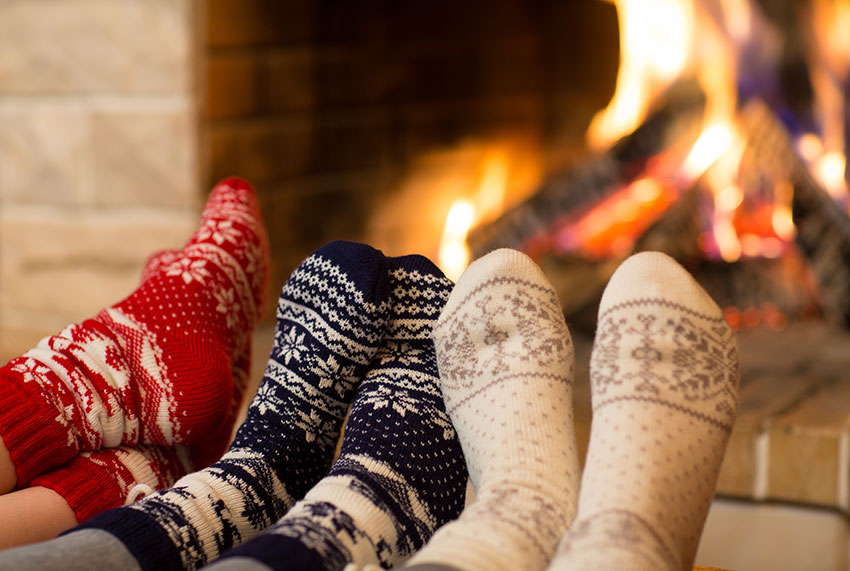 Three people warming their feet by the fire