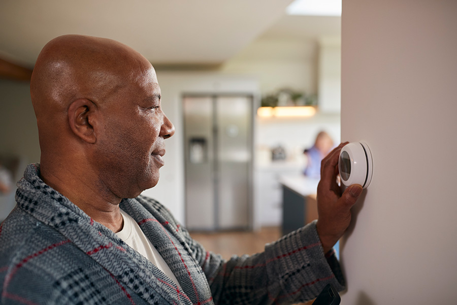 Man adjusts the temperature on a smart thermostat.
