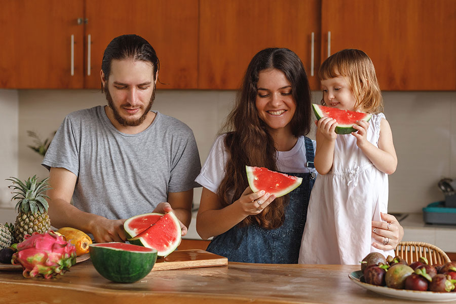 Family enjoying watermelon in cool home during the summer